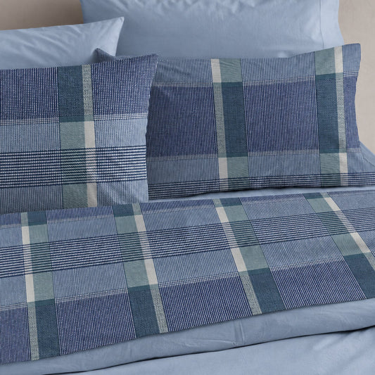 Completo lenzuola matrimoniale Castiglione Riviera blu con fantasia geometrica a quadri, ambientato sul letto