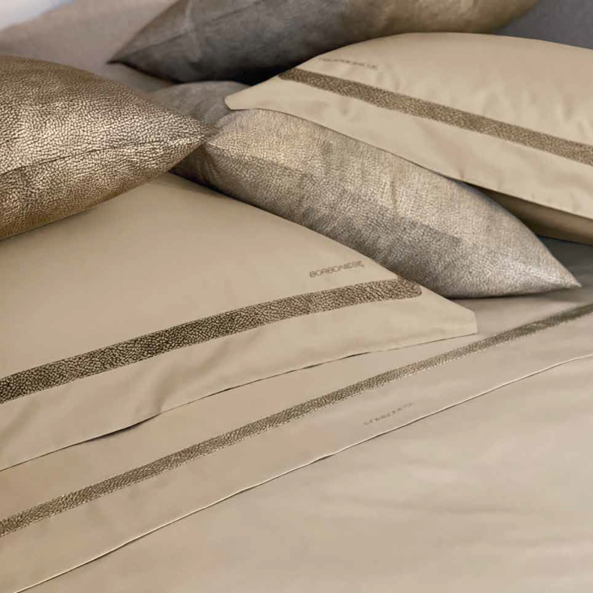 Completo lenzuola matrimoniale Borbonese Nastro ambientato sul letto con dettagli decorativi sulle federe.
