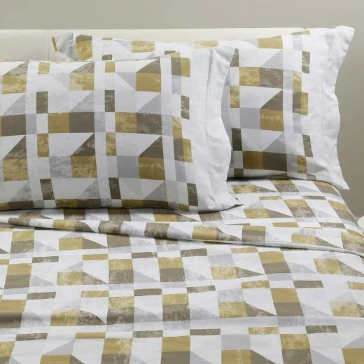 Completo lenzuola Cromatic Caleffi in flanella Oro ambientato su letto con fantasia a blocchi geometrici.