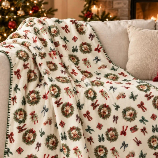 Plaid Teddy Bear Tessitura Randi con ghirlande di orsetti e fiocchi natalizi, ambientato su divano vicino all'albero di Natale.