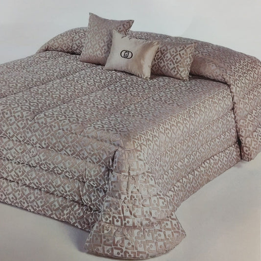 Trapunta matrimoniale Liu Jo New con monogramma LJ ambientata sul letto con cuscini coordinati