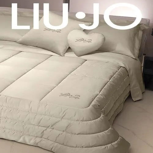 Trapunta matrimoniale Liu Jo Satin ambientata sul letto con cornici arrotondate e cuscini decorativi